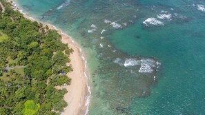 Vista aèria d'una platja amb aigües turqueses cristal·lines, sorra daurada i vegetació tropical exuberanta.
