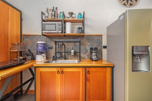 Cuina compacta amb microones, cafetera i dispensador d'aigua.