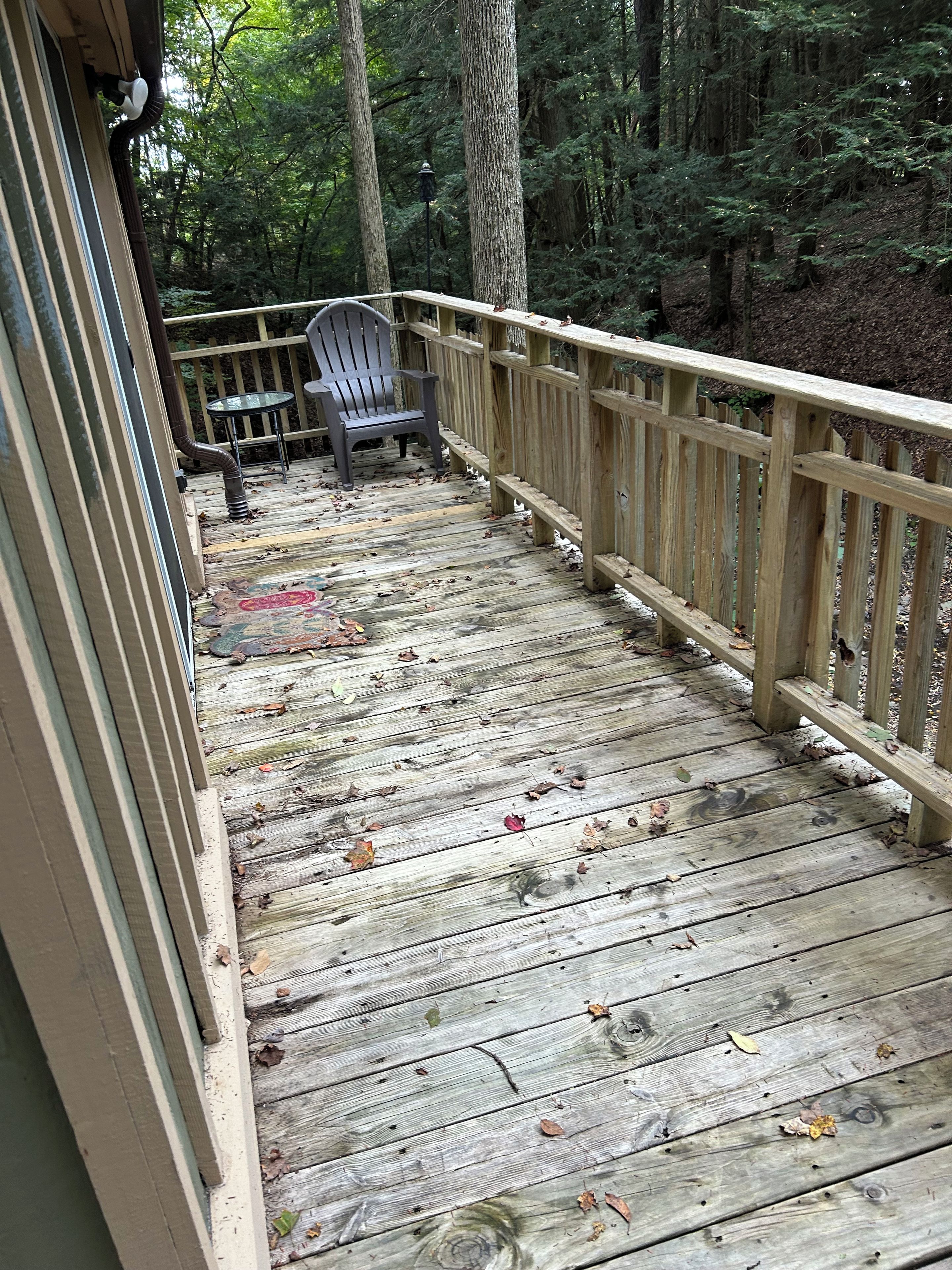 A wooden deck with a railing, a chair, and a table.