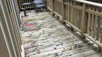A wooden deck with a railing, a chair, and a table.