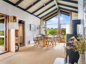 A spacious room with a high ceiling, a dining area with a round table and chairs, a bookshelf, and a large window offering a view of greenery. - "Anita" - 400m from the sea by Interhome (Bindslev)
