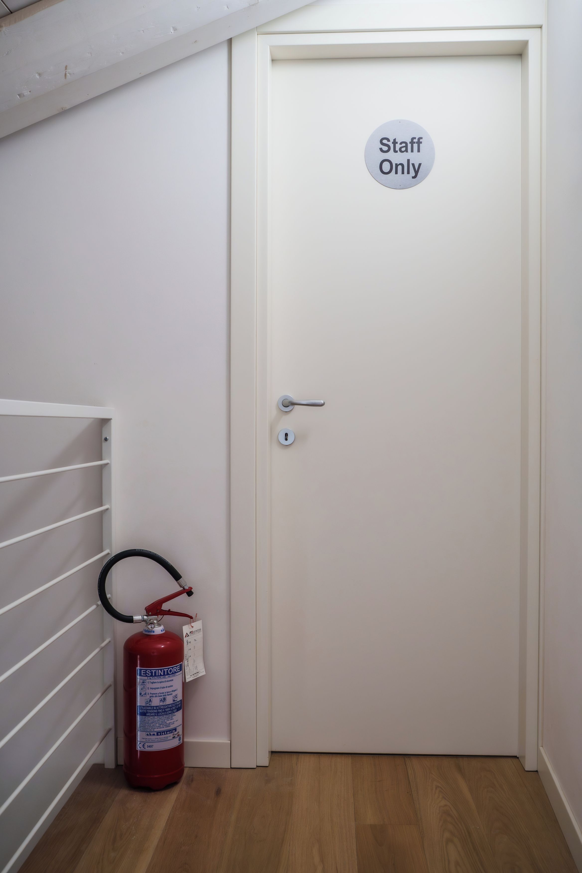 Een deur met een 'Alleen voor personeel'-bord, een brandblusser en een witte radiator.