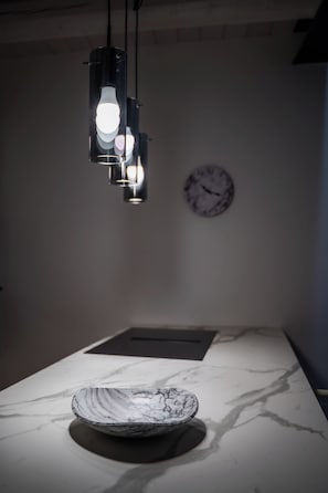 A marble countertop with a bowl, a wall clock, and pendant lights. - NEW! Urban Wine Studio Apt con terrazzo (Gorizia)