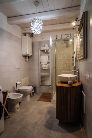 Een moderne badkamer met een toilet, wastafel met een decoratieve kom en een bidet.