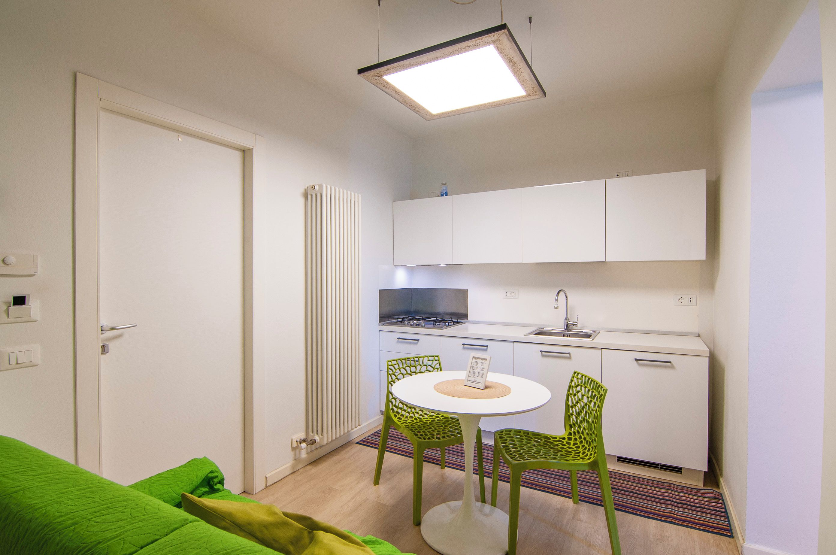 Una cucina compatta con angolo ristoro, un termosifone e una porta.