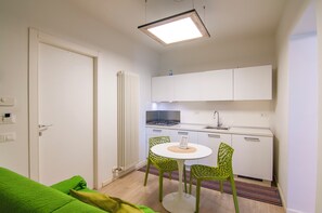 Een kleine keuken met een eethoek, een radiator en een deur.