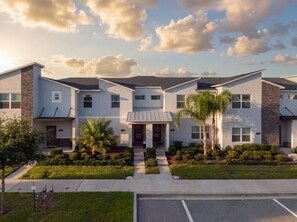 A multi-story residential building with a central entrance, surrounded by well-maintained landscaping and a parking area. - Magical Getaway With Private Pool, Top Location (Davenport)