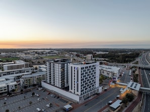 A multi-story hotel with a modern design, located near a highway with visible traffic.