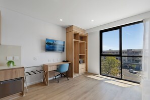 A modern office space with a desk, chair, and a large window offering a view of the city.