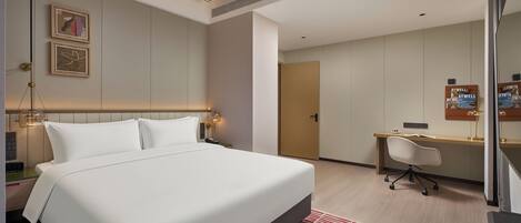 A modern hotel room with a large bed, bedside tables, a desk, and a chair.