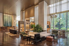 Un hall amplio con mostrador de recepción, zona de estar y grandes ventanales con vistas al exterior.