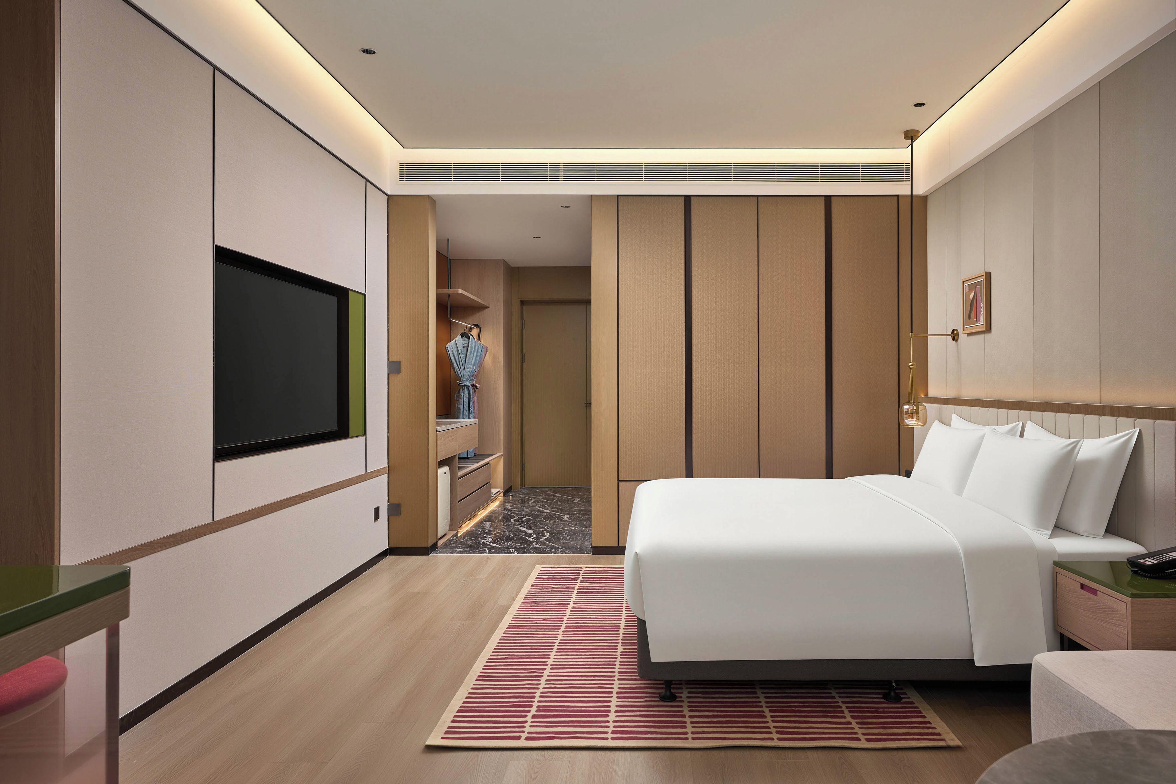Habitación de hotel moderna con una cama grande, un televisor de pantalla plana, un armario y un pequeño escritorio.