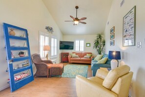 Ein Wohnzimmer mit blauem Bücherregal, Deckenventilator, Fernseher und Sofa.