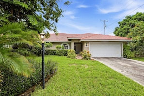 A single-story house with a red-tiled roof, a front garage, and a well-maintained lawn. - 3BR Near Beach & Delray in Boynton Beach (Boynton Beach)