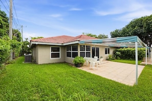 A house with a red-tiled roof, a covered patio with outdoor furniture, and a well-maintained lawn. - 3BR Near Beach & Delray in Boynton Beach (Boynton Beach)