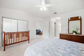 A bedroom with a bed, a wooden crib, a dresser, and a ceiling fan. - 3BR Near Beach & Delray in Boynton Beach (Boynton Beach)