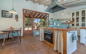 A kitchen with a central island, a dining table with chairs, a large window, and a ceiling with exposed beams. - Gorgeous home in SON SERVERA (SON SERVERA)