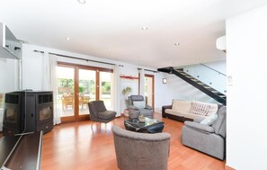 Ein modernes Wohnzimmer mit Sofa, Sesseln und Fernseher.