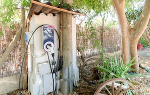 Eine Ladestation für Elektroautos im Freien mit Metallkonstruktion, einem Stromkabel und einem Solarpanel.