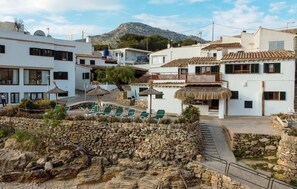 A coastal resort with white buildings, a pool area, and a stone wall. - Blue fisherman house 3 (POLLENÇA)