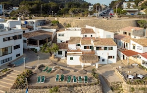 A coastal town with white buildings, a pool area with sun loungers, and a view of the sea. - Nice home in pollença with house sea view (POLLENÇA)