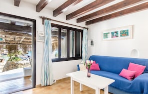 A room with a blue sofa, a white table, and a window with curtains. - Nice home in pollença with house sea view (POLLENÇA)