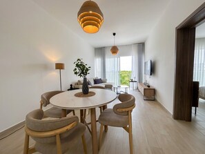Ein modernes Wohnzimmer mit einem runden Esstisch, zwei Stühlen, einem Sofa und einem Fernseher.