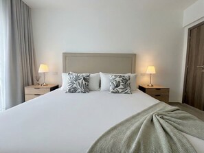 Una habitación de hotel con una cama grande, dos lámparas de noche y un cabecero de madera.