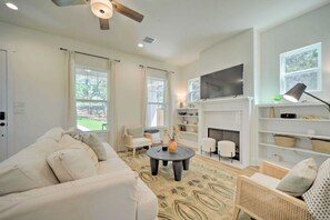 A living room with a sofa, a coffee table, a fireplace, and a television. - Canyon Lake Cottage w Deck, Grill & Fast WiFi! (Canyon Lake)