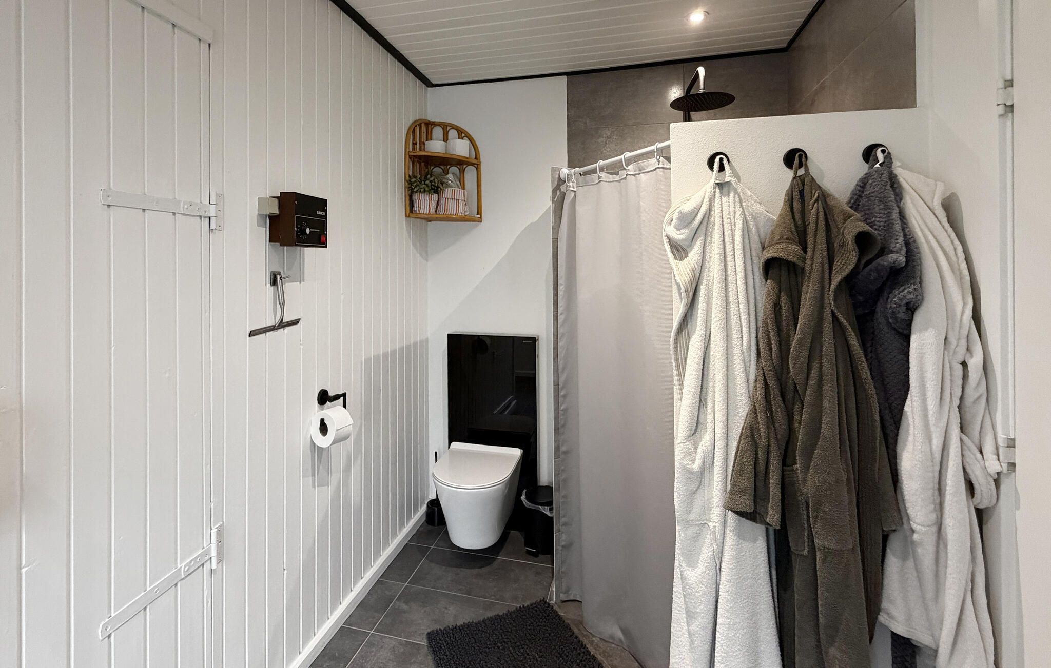 Une salle de bain équipée de toilettes, d’une douche et d’un porte-serviettes.