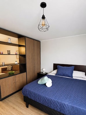 A bedroom with a bed, a nightstand, a wardrobe, and a pendant light. - Cozy Apartment in fantastic Santiago near to Movistar Arena and Club Hipico (santiago)