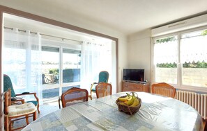 Un comedor con una mesa, sillas, un televisor y vistas al exterior.