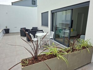 A patio with a table and chairs, a potted plant, and a sliding glass door leading to an indoor area. - LJR Accommodations São Vicente Ferreira (Ponta Delgada)