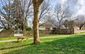Ein Park mit einer Bank, einer Steinmauer und Bäumen.