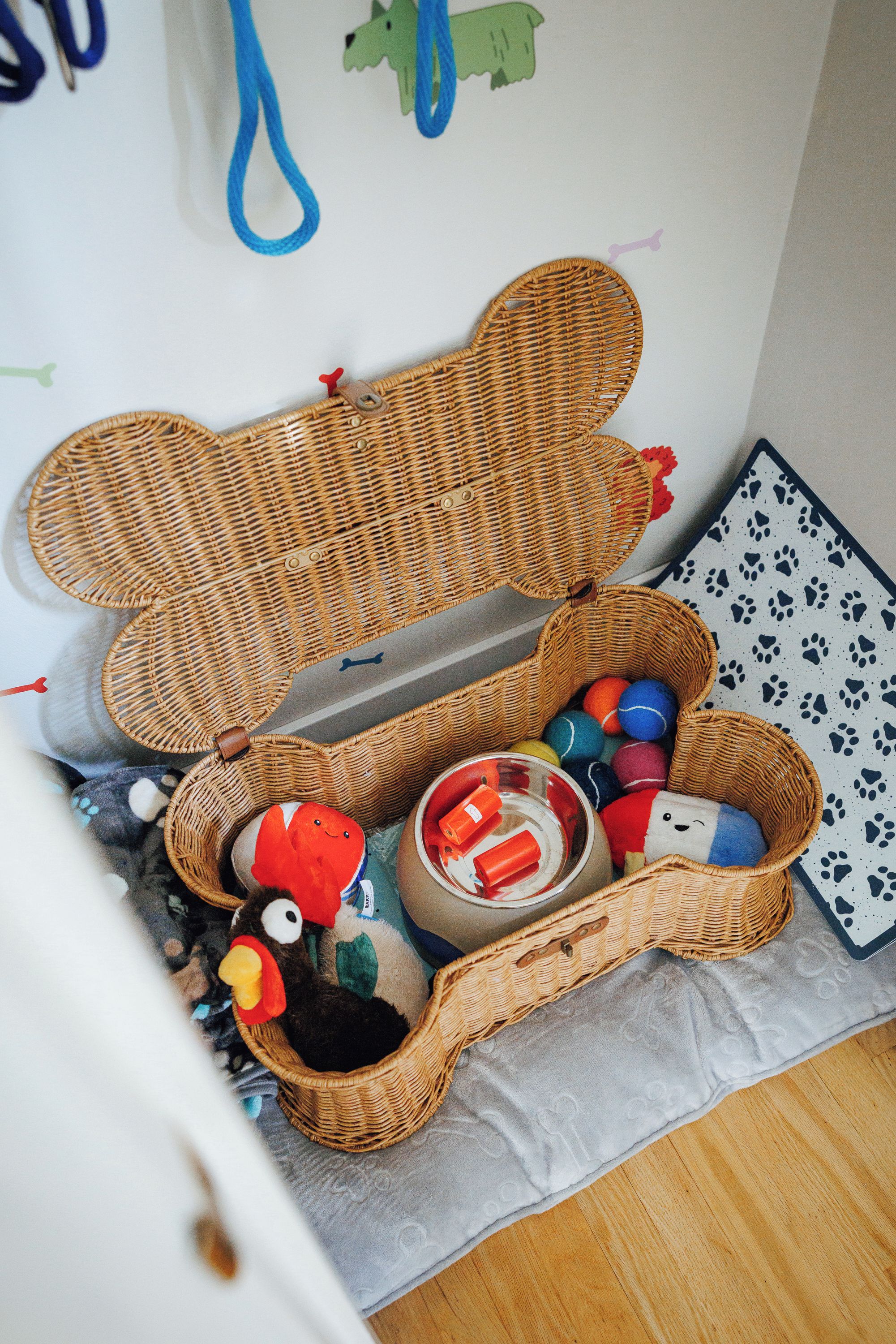 Zona de juegos infantil con dos cestos de mimbre, uno abierto y otro cerrado, que contienen juguetes y un peluche.