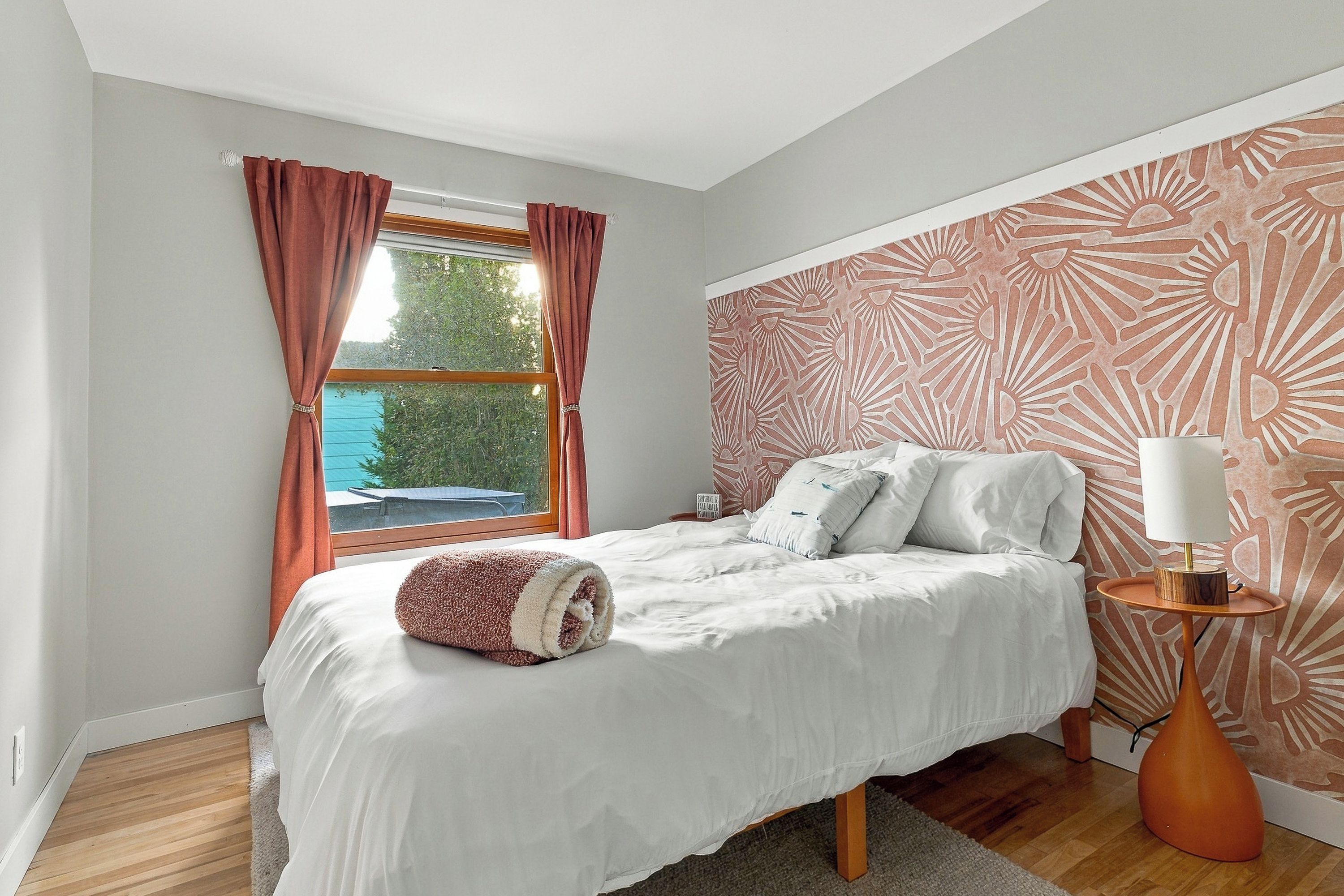 Bright, cozy bedroom with designer accent wall and natural light