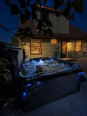 A hot tub in front of a house with a porch and a window. - 2BR Lake Superior Stay | Hot Tub + Walk Downtown (Ashland)