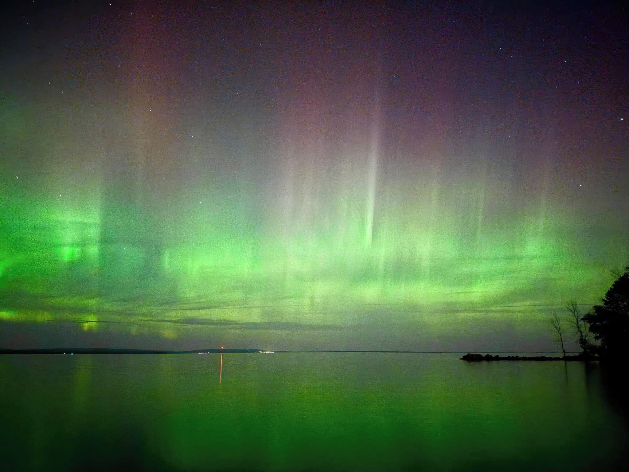 A night sky with the aurora borealis over a calm body of water.