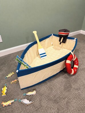 A toy boat with a paddle, life preserver, and toy fish on a carpeted floor. - 2BR Lake Superior Stay | Hot Tub + Walk Downtown (Ashland)