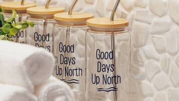 Eine Reihe von klaren Glasbehältern mit Holzböden und Metallhalmen, beschriftet mit 'Good Days Up North', auf einer Marmorplatte platziert.