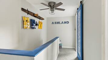 A hallway with a ceiling fan, a wall-mounted sign reading 'ASHLAND,' and a blue railing.