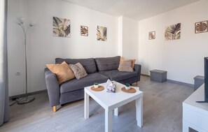 A modern living room with a grey sofa, white coffee table, and artwork on the walls.