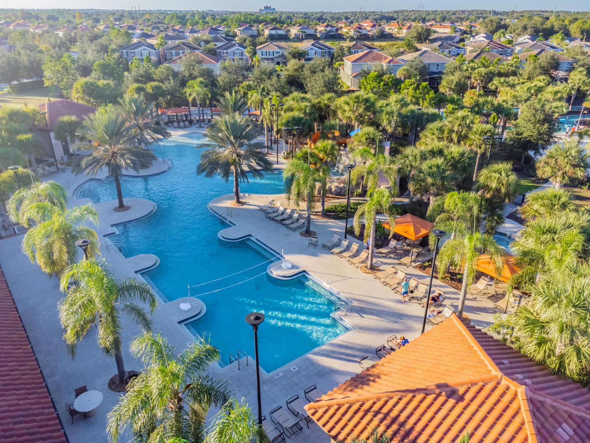 A resort with a central swimming pool surrounded by palm trees and lounge chairs.