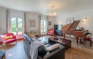 Ein Wohnzimmer mit einem Flügel, einem Sofa, einem Fernseher und einem Esstisch.
