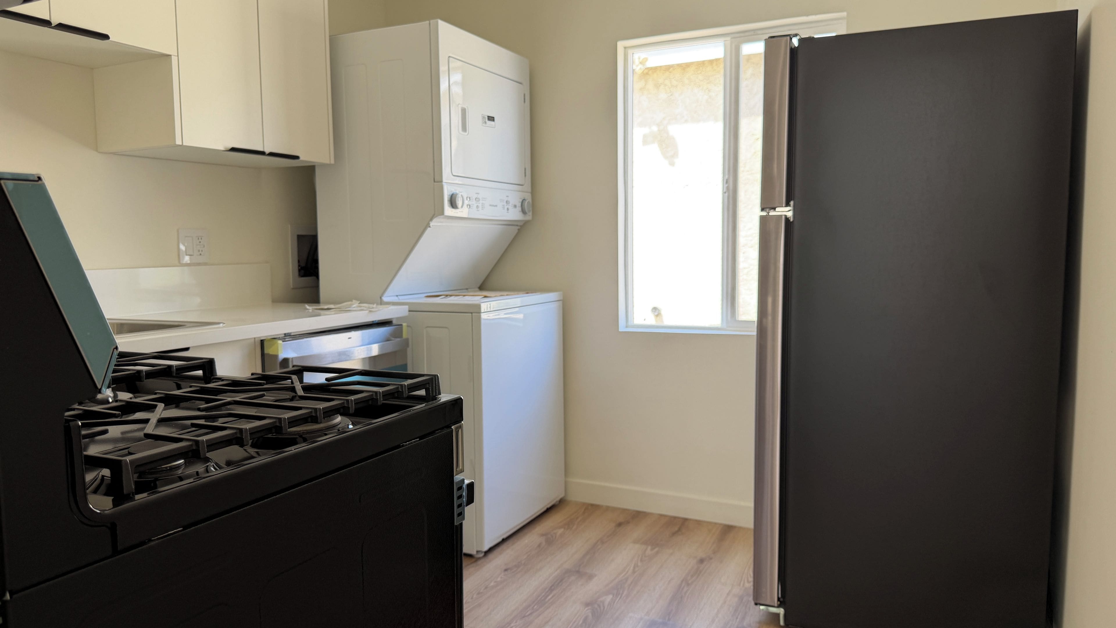A kitchen with a gas stove, a white dishwasher, and a black refrigerator.