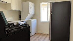 A kitchen with a gas stove, a white dishwasher, and a black refrigerator. - The Imperial Studios (Los Angeles)