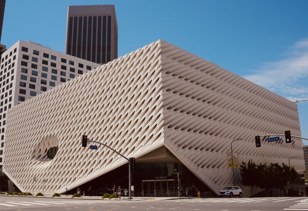 A modern building with a unique geometric facade, located at a city intersection.