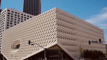 A modern building with a unique geometric facade, located at a city intersection.
