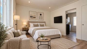 A bedroom with a bed, bedside table, lamp, and artwork on the wall.