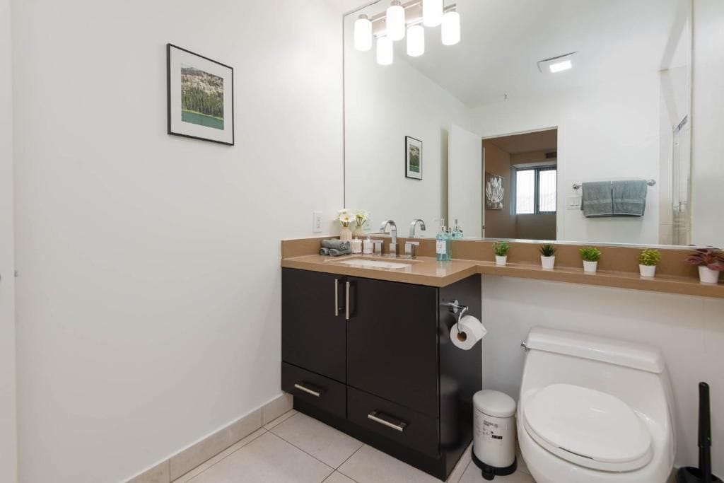 A modern bathroom with a toilet, sink, and mirror.